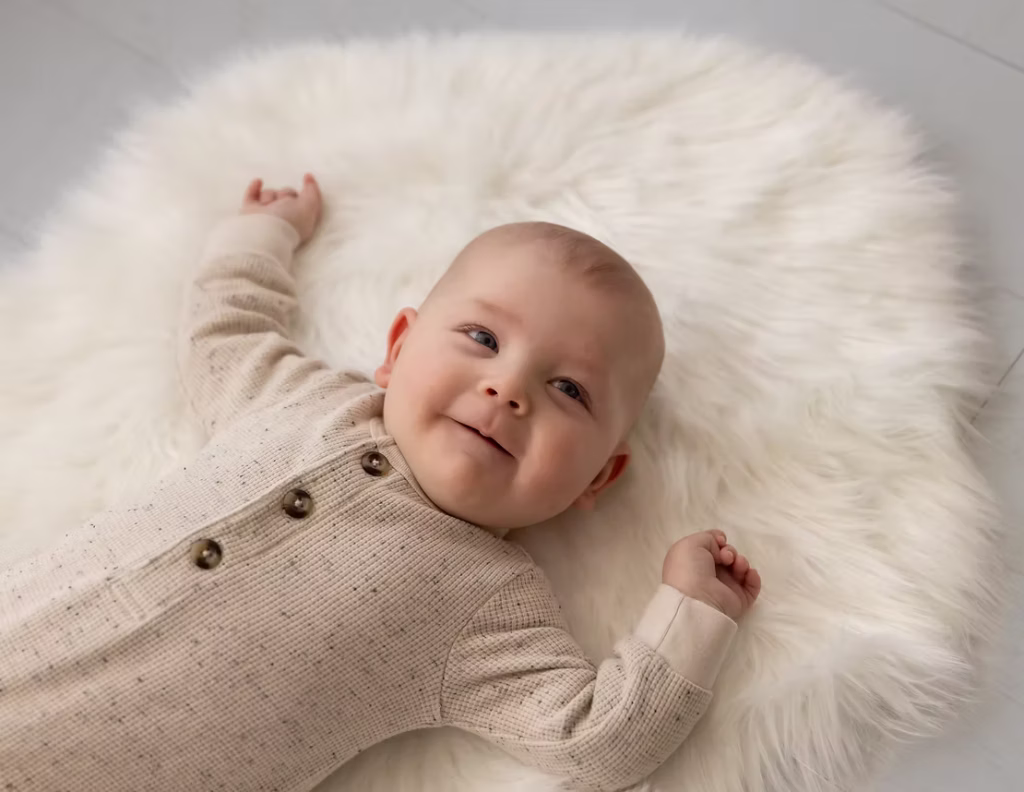 This happy baby is cozy on the fur blanket and white floors of the photo studio
